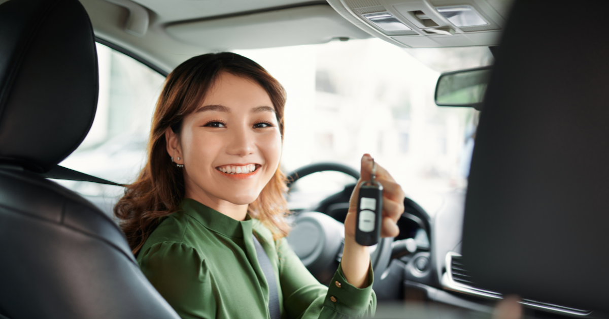 a young woman sitting in a car with her key after a lease buyout with RTA