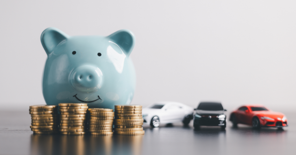 A piggy bank with toy model cars and money displaying budgeting and saving for a car