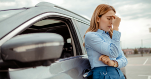 Woman standing outside a vehicle in Ontario with her hand over her face frustrated looking for help with vehicle financing